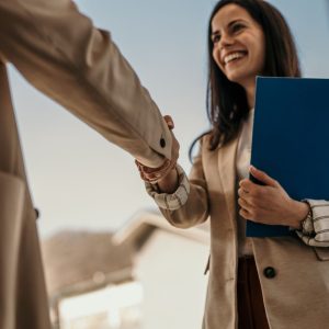 Woman shaking hands and holding a clipboard