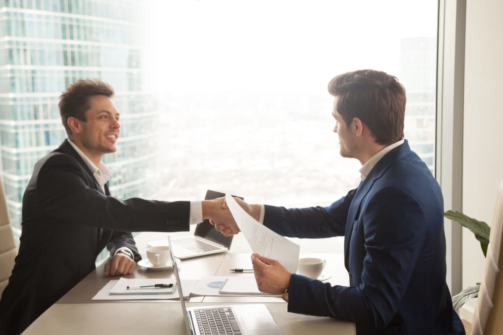 two business men shaking hands after securing a deal